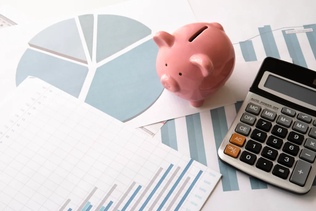 Calculadora, cofrinho e planilhas com gráficos para organização financeira e controle de despesas