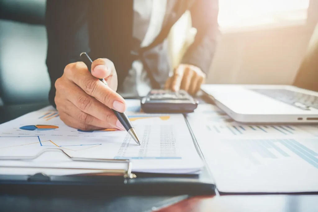 Consultor financeiro de terno com calculadora fazendo contas e analisando gráficos, exemplo de planejamento financeiro estratégico