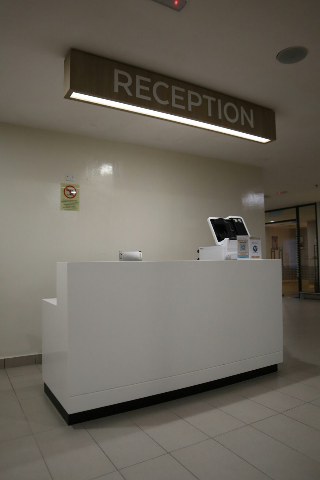 Balcão de recepção moderno de um centro médico, com placa sinalizadora acima
